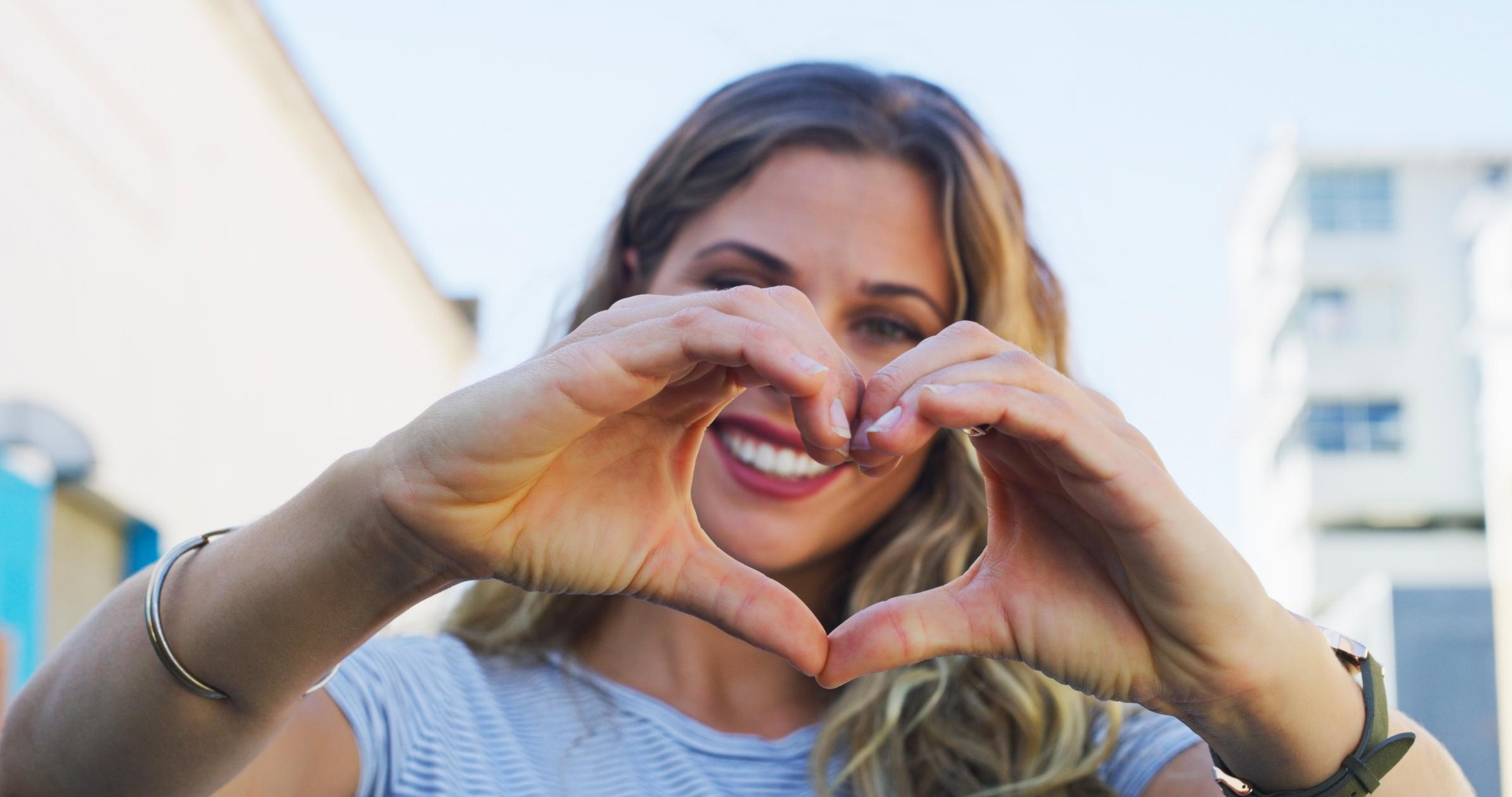 Smiling woman with hands in the shape of a heart